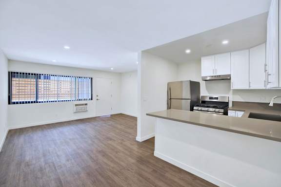 A kitchen with white cabinets and a wooden floor.
