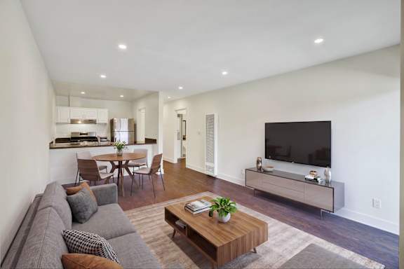 A modern living room with a grey sofa, a wooden coffee table, and a flat screen TV.