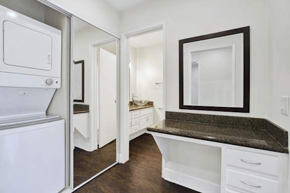 A white kitchen with a granite counter top and a refrigerator.