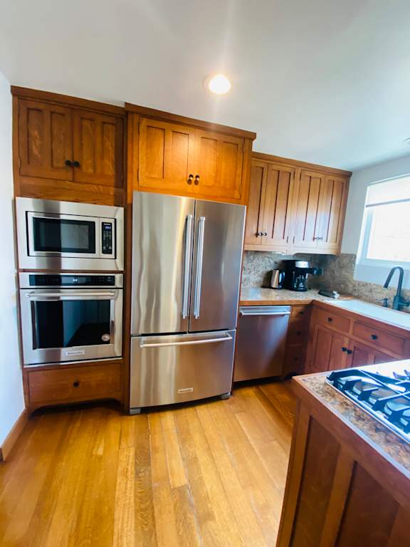 a kitchen with stainless steel appliances and wooden cabinets at 8535 Colgate-Fully Furnished Apartments, Los Angeles, CA, 90048