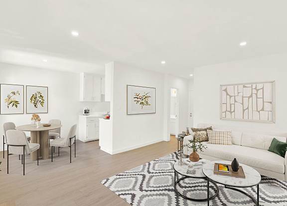 A living room with a white couch, a dining table with chairs, and a rug on the floor at Bonnie Brae Apartments, California, 90006