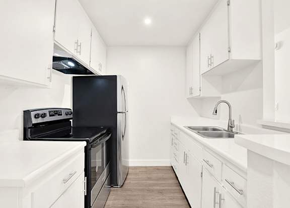 A kitchen with black appliances and white cabinets at Bonnie Brae Apartments, California, 90006