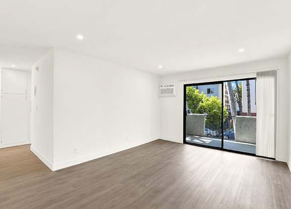 A room with a wooden floor and a sliding glass door at Bonnie Brae Apartments, California