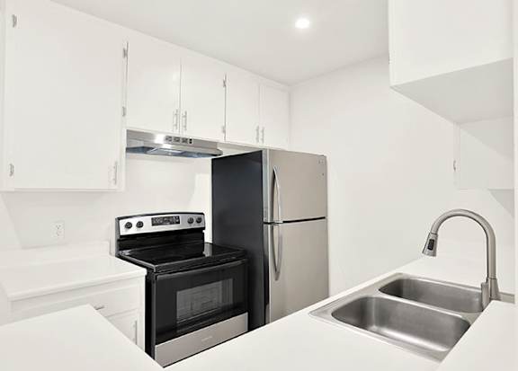 A black oven and fridge in a white kitchen at Bonnie Brae Apartments, Los Angeles, California