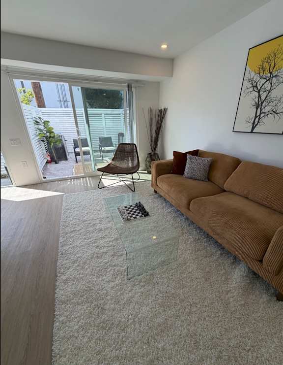 A living room with a brown couch and a glass coffee table.
