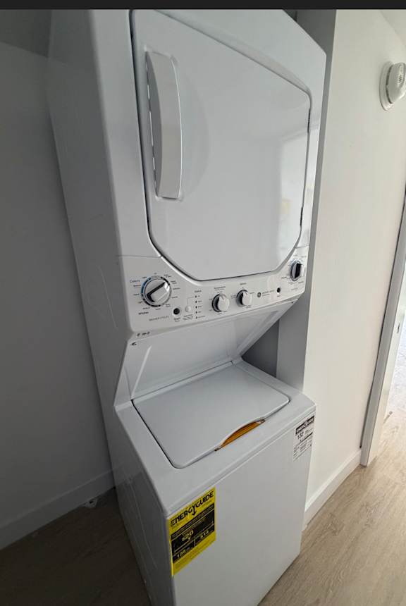 A white washing machine with a yellow caution label on the front.