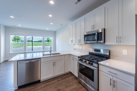 an empty kitchen with white cabinets and stainless steel appliances