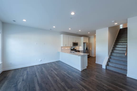 a living room with a staircase and a kitchen in a house