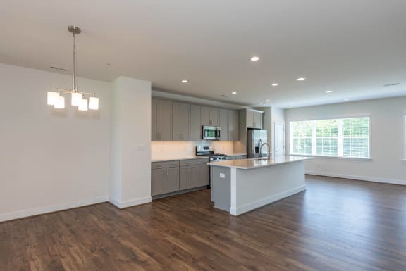 an open kitchen and living room with white walls and wood flooring