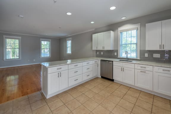 a large kitchen with white cabinets and tiled floors