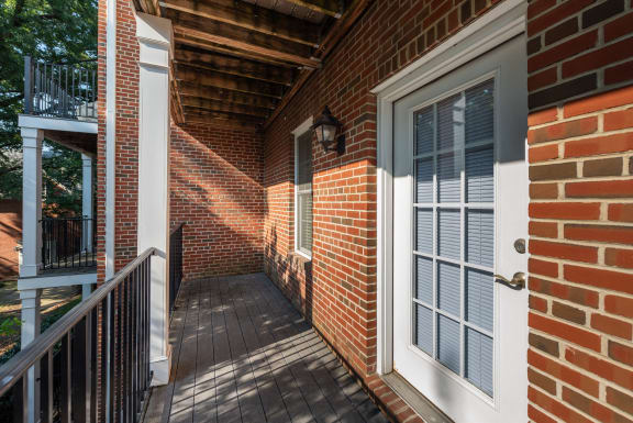 the front porch of a brick house with a white door