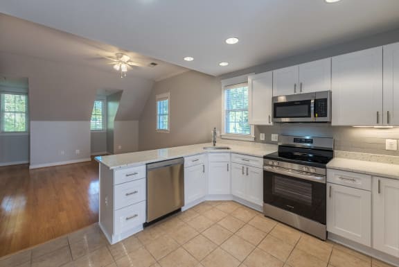 an empty kitchen with white cabinets and stainless steel appliances