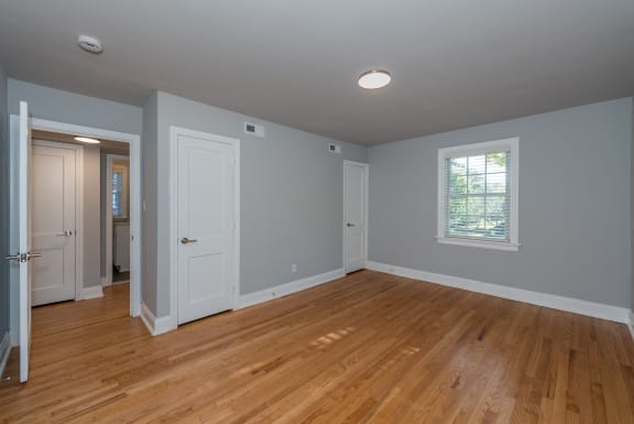 an empty living room with wood floors and a window