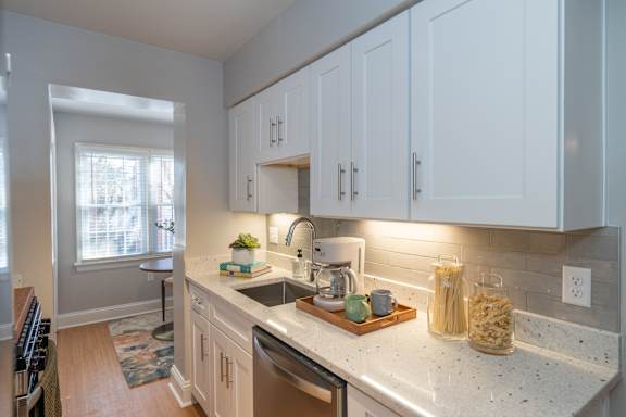 A kitchen with white cabinets and a marble countertop.