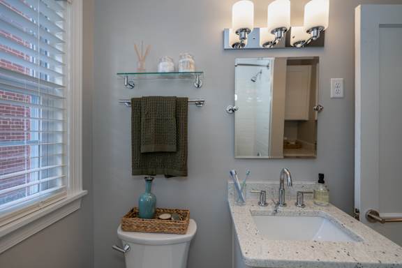 A bathroom with a toilet, sink, and mirror.