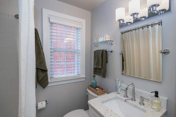 A bathroom with a white sink and a window with blinds.