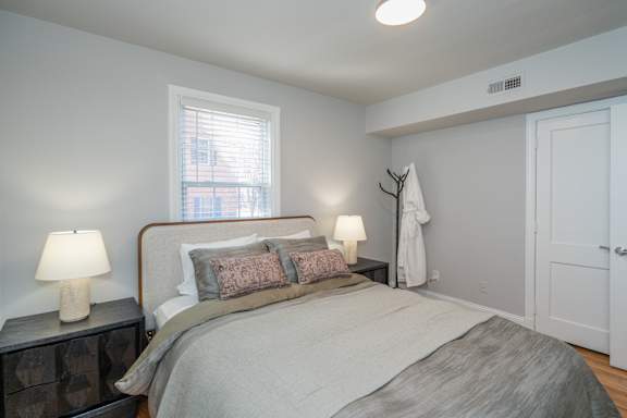 A bedroom with a bed, nightstand, and window.