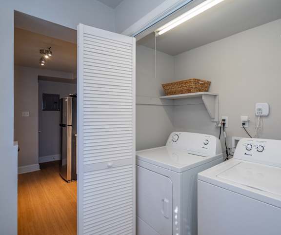 A laundry room with a basket on the shelf and two washing machines.
