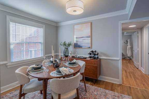 A dining room with a table set for two and a painting on the wall.