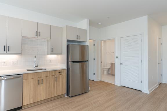 A kitchen with a refrigerator, sink, and cabinets.