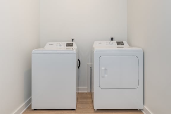 Two white washing machines in a laundry room.