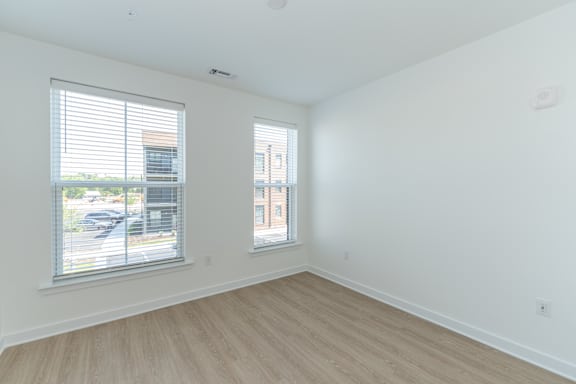 A room with two windows and wooden flooring.