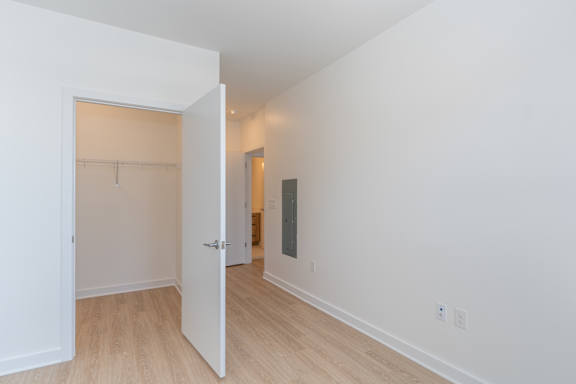 A room with a white door and a wooden floor.