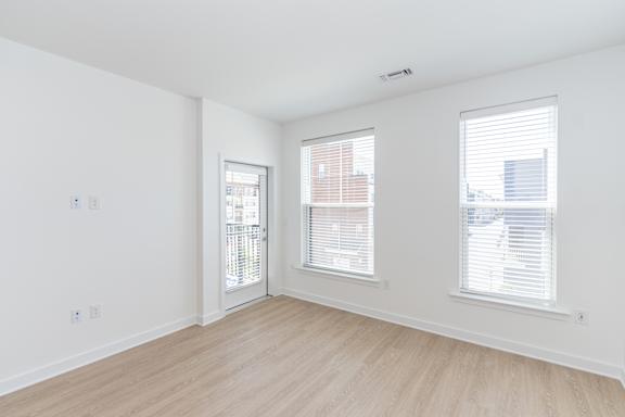 A room with a white wall and a window with blinds.