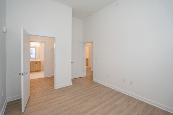 Large primary bedroom with tall ceilings and walk through closet to bathroom