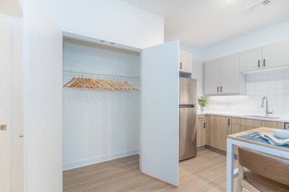 A kitchen with a white refrigerator, wooden floor, and a table with a blue cloth on it.