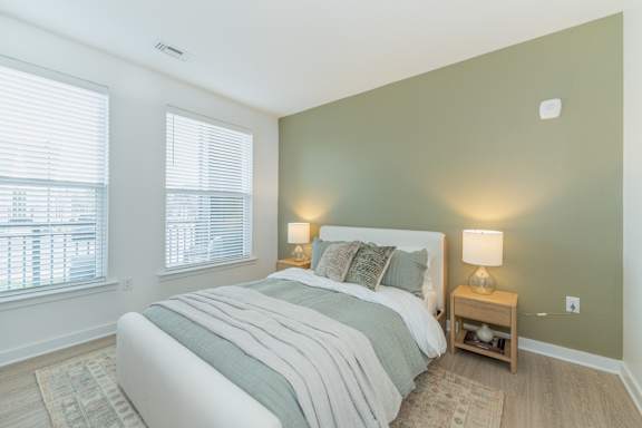 A bedroom with a large bed and two lamps.