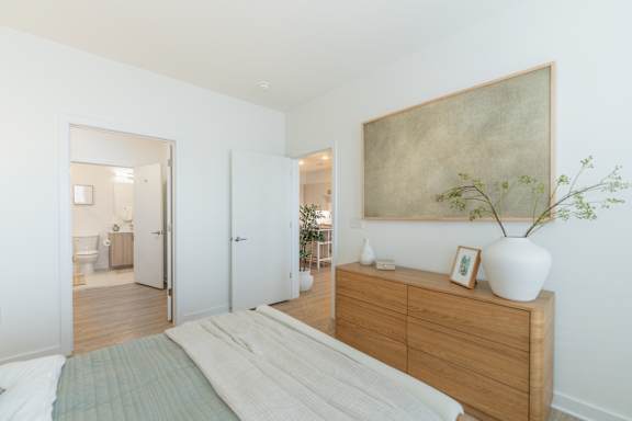A bedroom with a bed, dresser, and a painting on the wall.