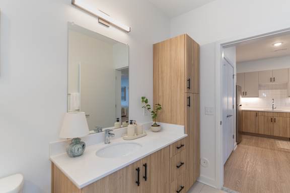 A bathroom with a sink, mirror, and wooden cabinets.