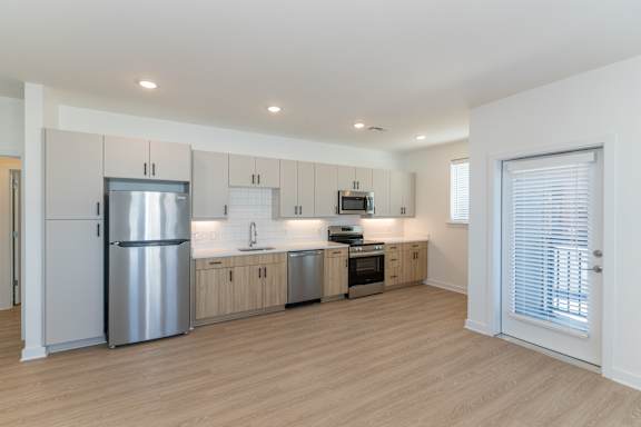 A modern kitchen with wooden floors and stainless steel appliances.