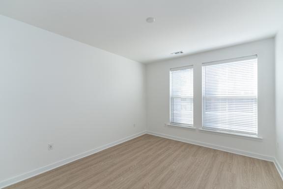 A room with wooden flooring and a window with blinds.