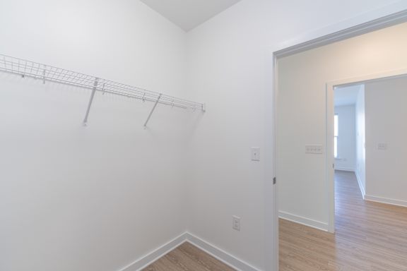A white wall with a shelf and a doorway leading to another room.