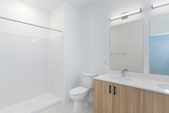 A white toilet sits in a bathroom with a sink and mirror.