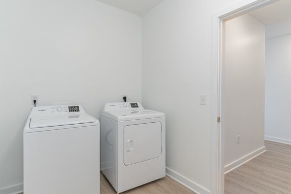 Two white front load washing machines in a white room.