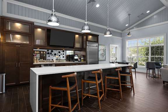 A kitchen with a white island and wooden chairs. at Merion at Cross Keys Apartments, Williamstown, 08094