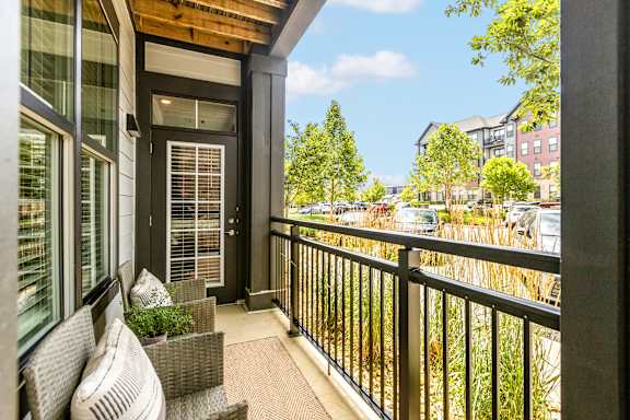 A balcony with a chair and a table with a potted plant on it.