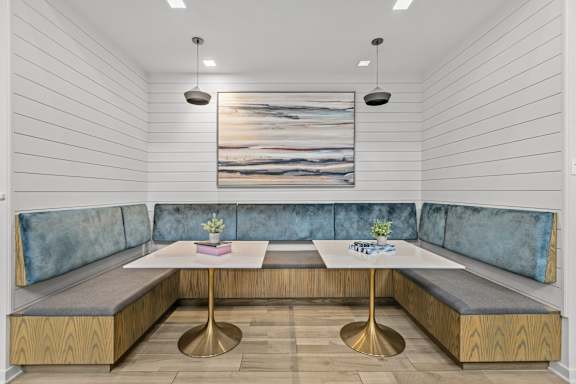 A modern dining area with a wooden table and blue cushioned booths.