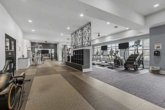 A gym with a variety of equipment including treadmills, stationary bikes, and weight machines.
