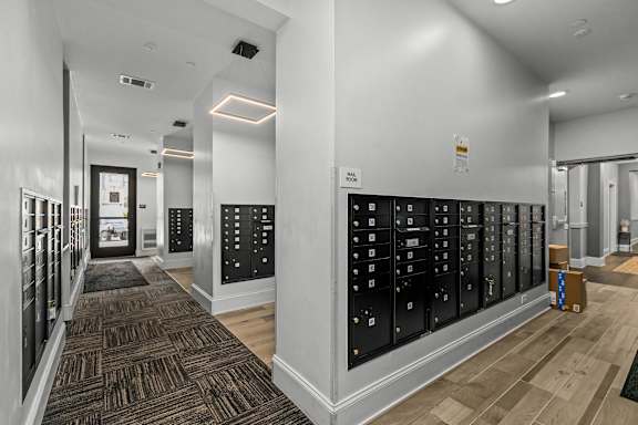A hallway with a carpeted floor and a wall of lockers on the right side.
