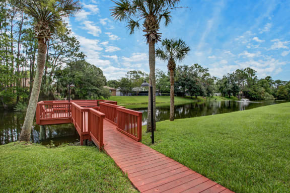 a red bridge over a body of water with palm trees at Timberwalk at Mandarin Apartment Homes, Florida, 32257