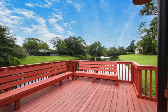 a large wooden bench on a deck overlooking a pond at Timberwalk at Mandarin Apartment Homes, Florida, 32257