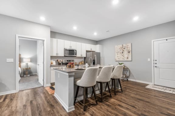 a kitchen with white cabinets and a counter top with chairs