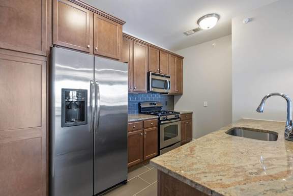 A kitchen with a granite counter top and stainless steel appliances.