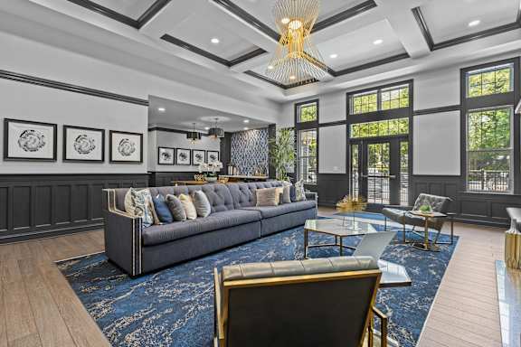 A large, elegant living room with a dark blue sofa and a chandelier.