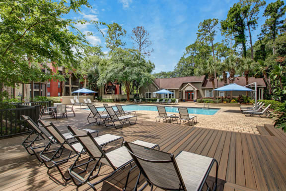 a swimming pool with chairs and tables on a wooden deck at Timberwalk at Mandarin Apartment Homes, Florida, 32257