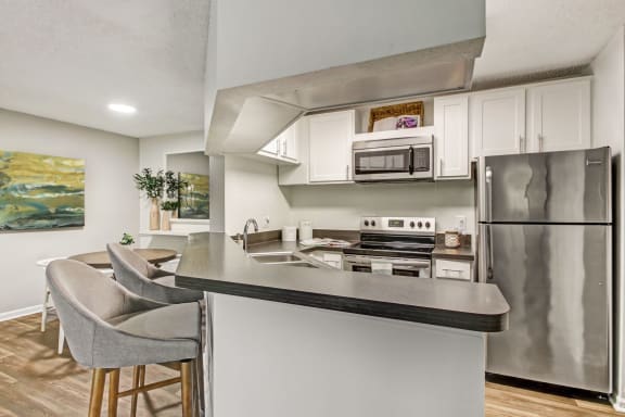 a kitchen with stainless steel appliances and a counter with chairs at Timberwalk at Mandarin Apartment Homes, Florida, 32257
